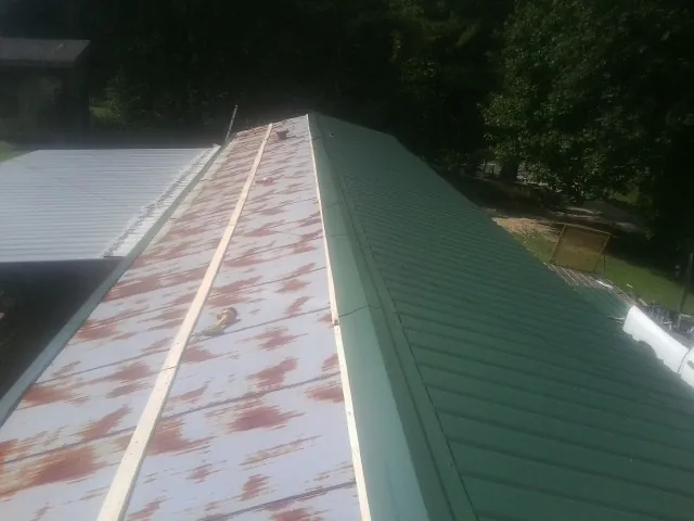 Old rusted panels beside newly installed green metal roofing — Wind Damage Roof Repair by Roofing Brothers in Herkimer
