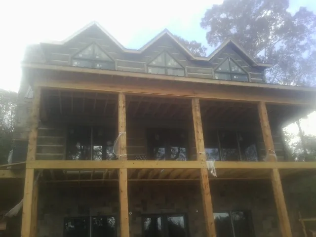 Dormers and porch framing on a large log home under construction — Roof Coating work by our crew in Herkimer