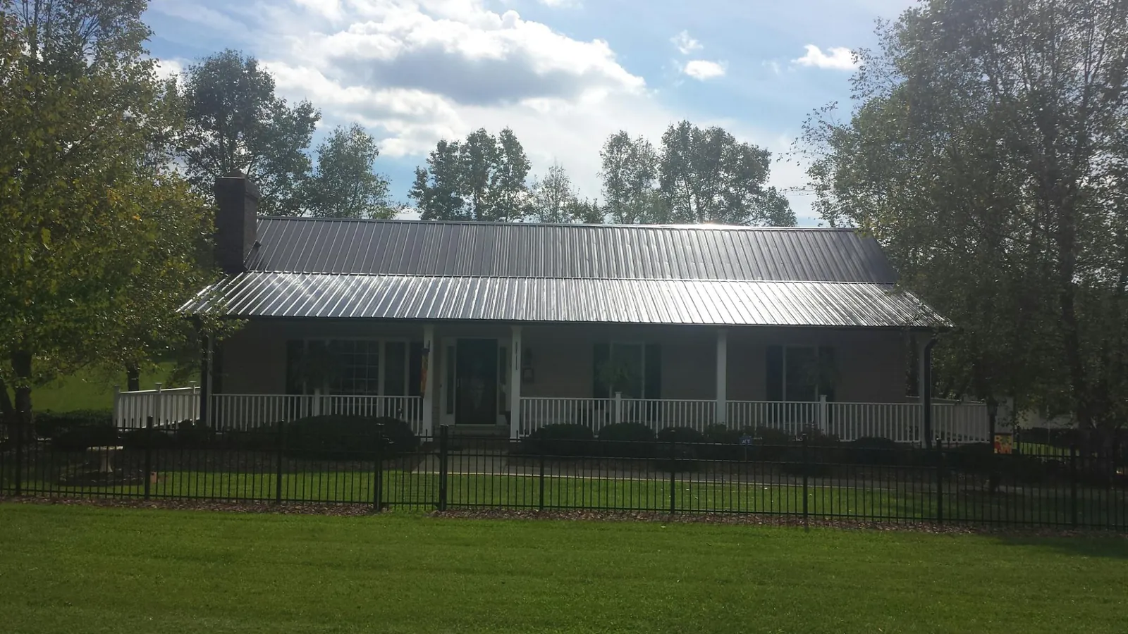 Gray metal roof on a brick ranch with a full width front porch — Gutter Guard Installation work by our crew in Herkimer