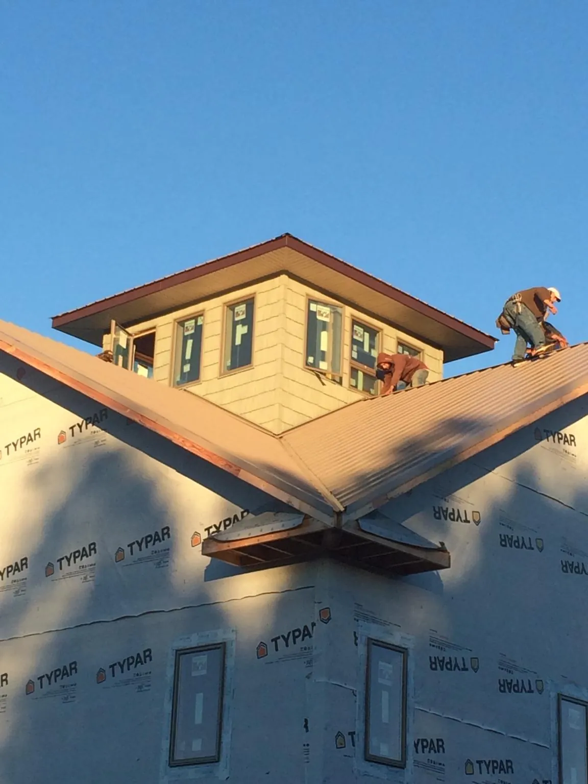 Roofers working around a rooftop cupola on a new metal roof at sunset — Roof Waterproofing in Herkimer by Roofing Brothers